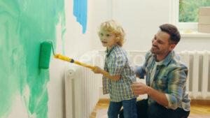 Father and Son Painting a Wall in Their Home with a Roller Envato Elements